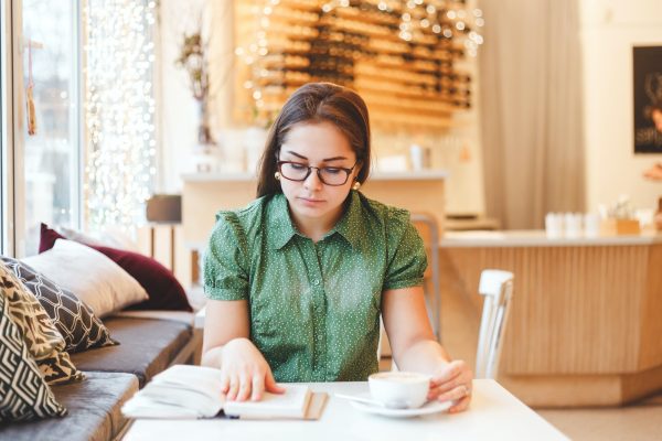 Beautiful young woman relaxing and reading a book in coffee shop Beautiful young woman relaxing and reading a book in coffee shop